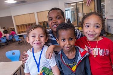 Four students pose for a photo in a classroom